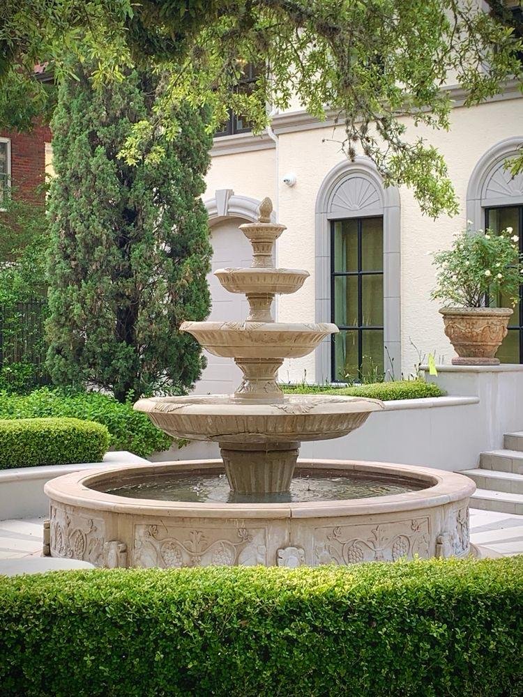 Carved marble three tier fountain placed in a landscaped garden courtyard