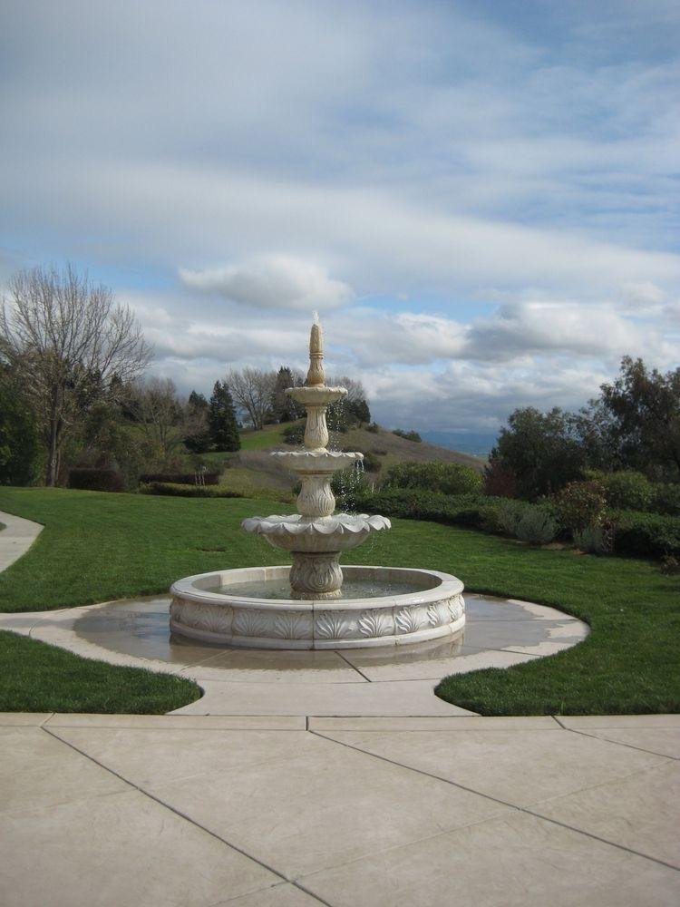 Marble and sandstone multi-tier outdoor water fountain installed in open landscaped garden area