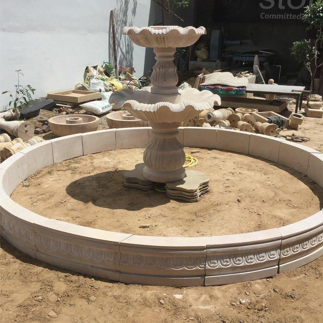 Marble and sandstone multi tier outdoor water fountain under installation with circular stone basin=