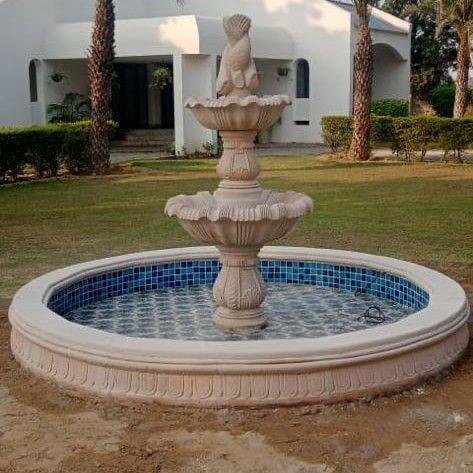 Marble and sandstone multi-tier outdoor water fountain installed in landscaped garden area