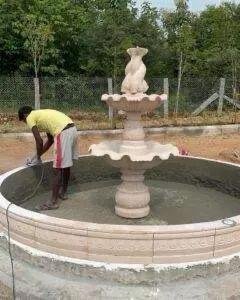 Marble and sandstone tiered outdoor water fountain during installation in garden landscape